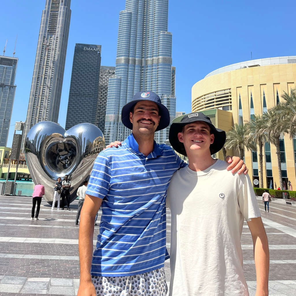Liam and another man standing together and smiling in the city.
