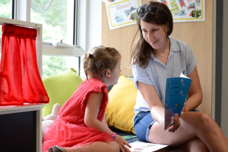 Girl reading at playgroup with mum