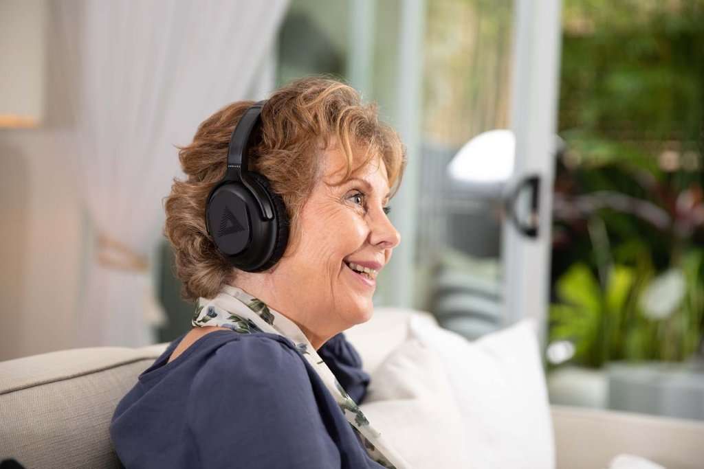 Woman smiling and wearing over-the-ear headphones.