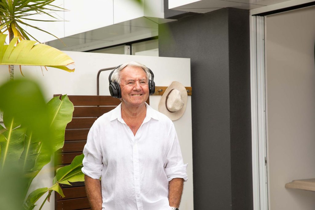 Man wearing over-the-ear headphones and smiling outside.