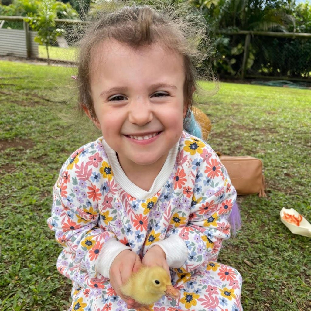 Five year old Charlotte smiling and holding a duckling.
