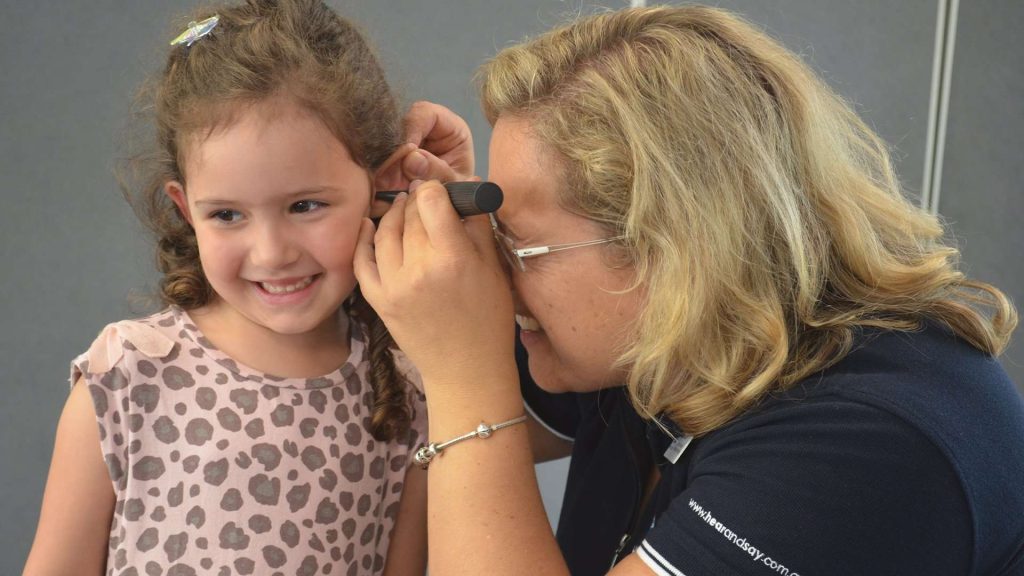 Women Looking In Girls Ear For Hearing Test