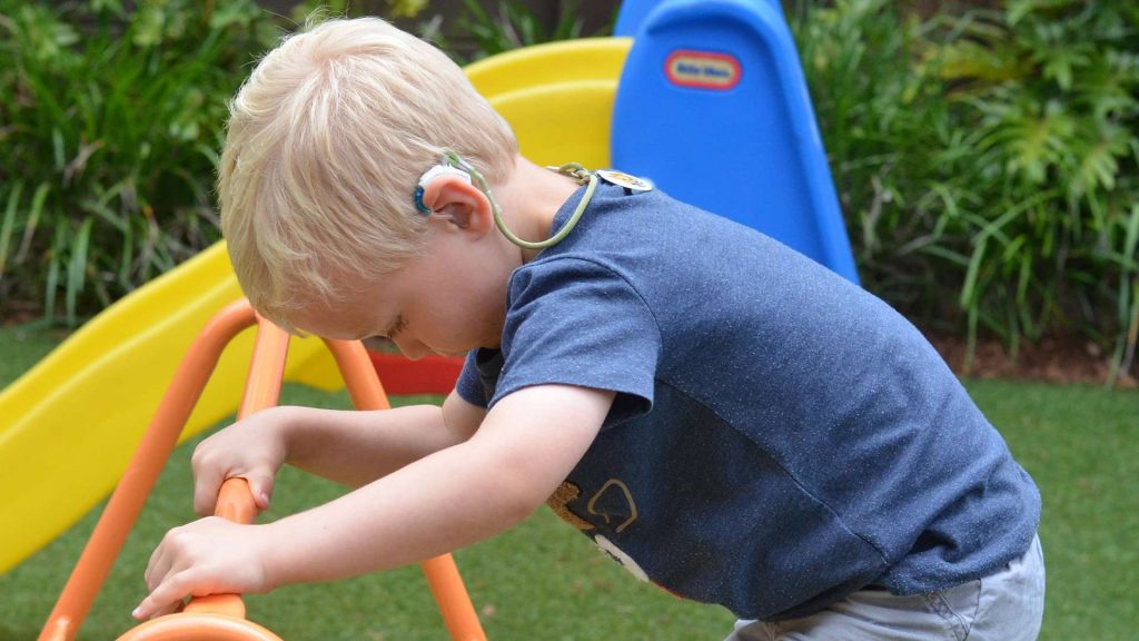 Child with hearing aid playing on the playground.