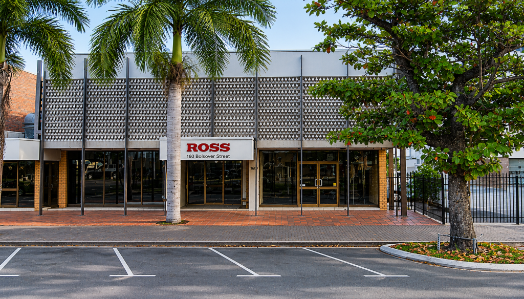 Modern commercial building at 160 Bolsover Street Rockhampton, now home to Hear and Say from 2026, with glass frontage, palm trees, and empty street parking spaces