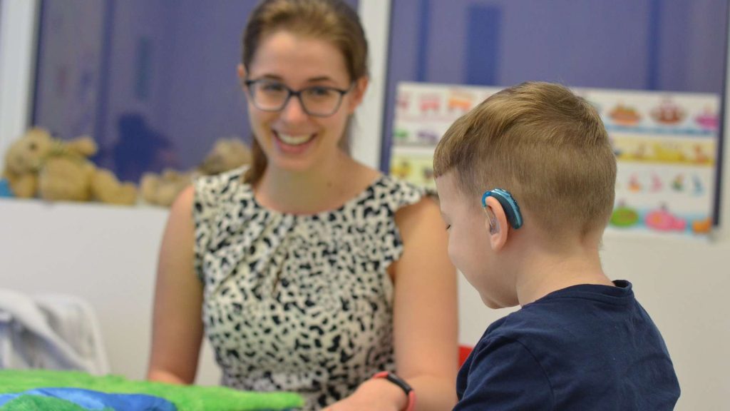 Boy with hearing aid in speech therapy session.