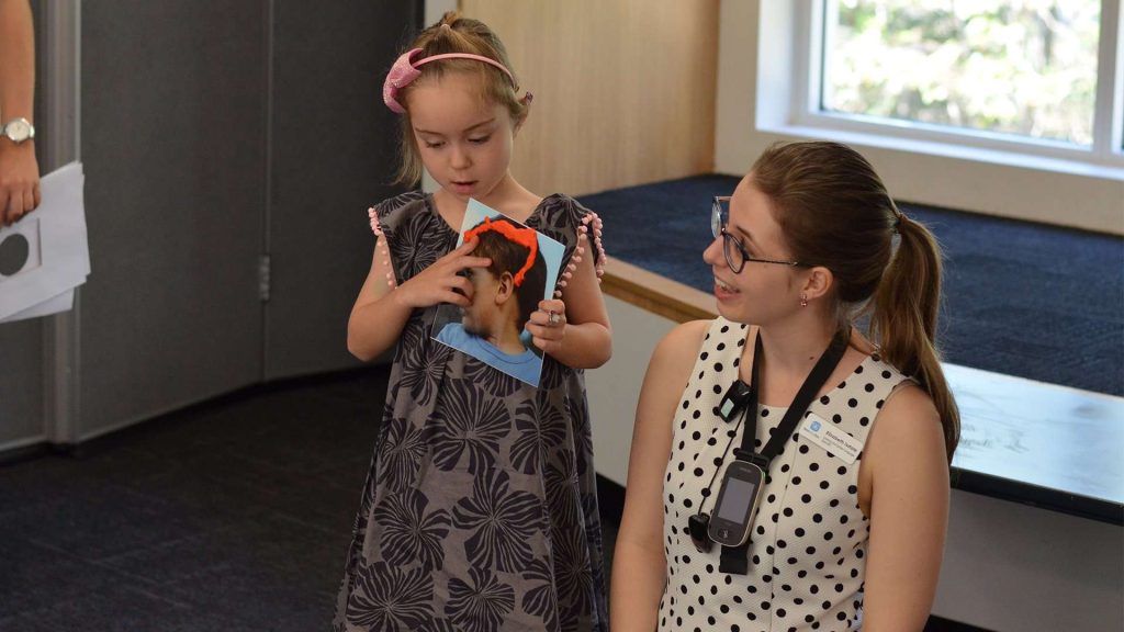 Girl with speech pathologist wearing assistive listening device.