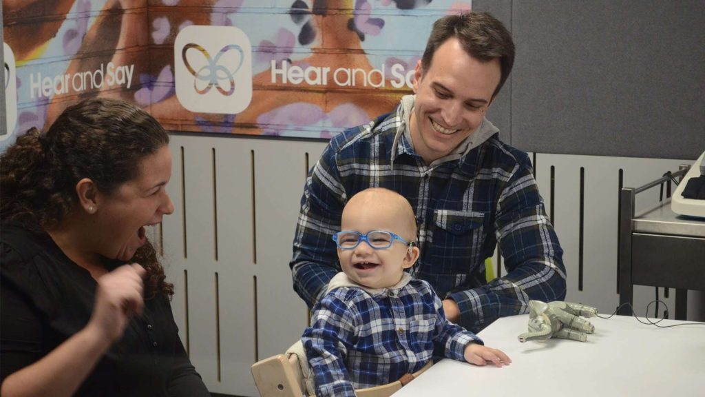 Child, dad and speech therapist laughing together.