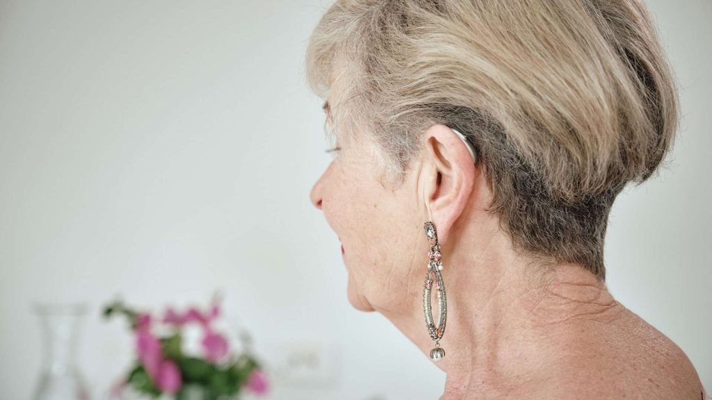 Older lady with behind-the-ear hearing aid from behind.