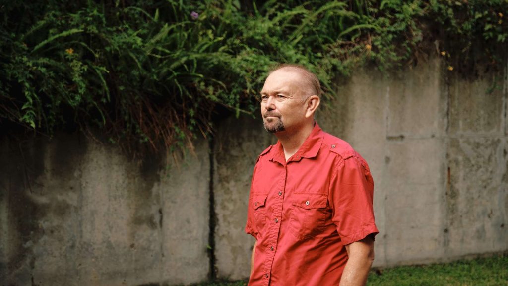 Man in red shirt walking outdoors.